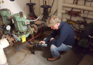 Person working on plumbing in a basement with tools and equipment.